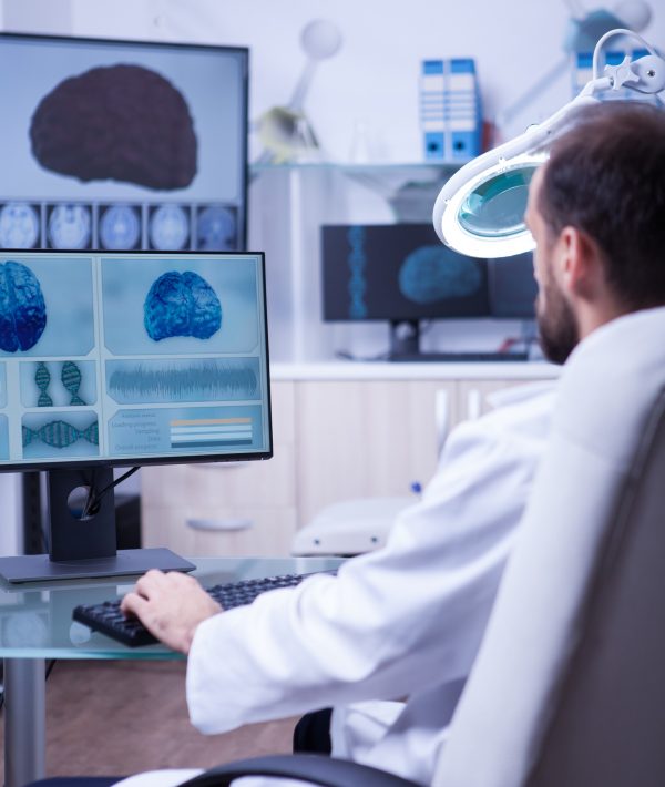 Doctor in white coat sitting at his desk in the hospital typing on his computer. Radiologist at work.